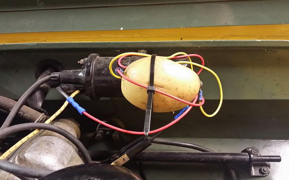 Mechaniker repariert Auto mit Kartoffel
