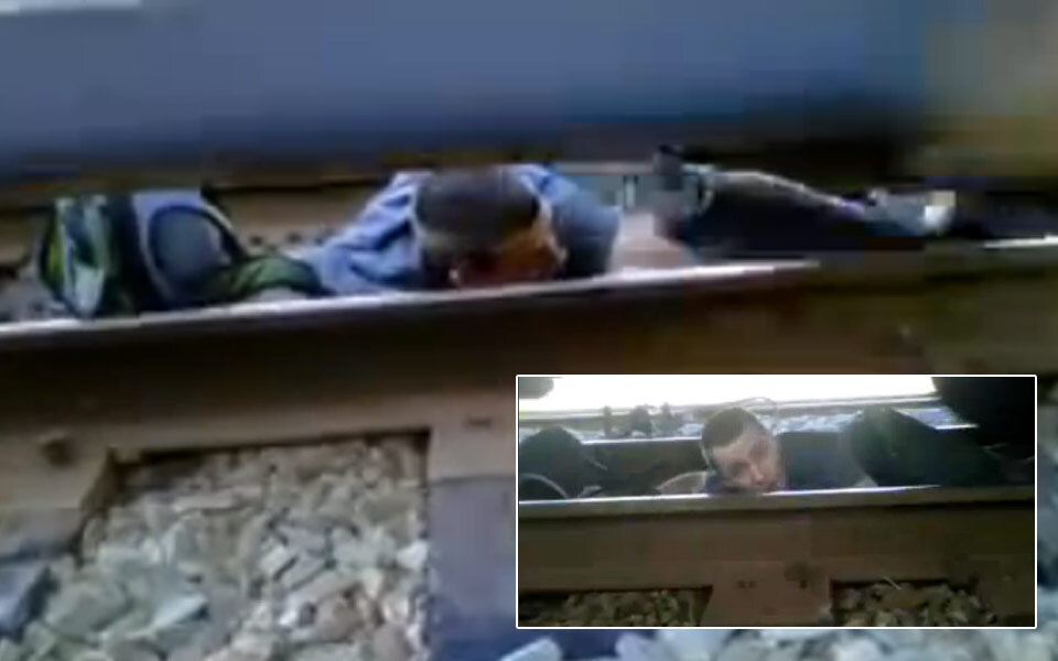 Mann quert Schienen unter fahrendem Zug 