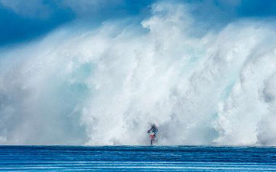 Irrer Typ surft mit Motorrad übers Meer